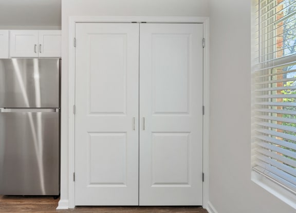 a kitchen with white doors and a stainless steel refrigerator