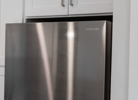 a stainless steel refrigerator in a kitchen with white cabinets