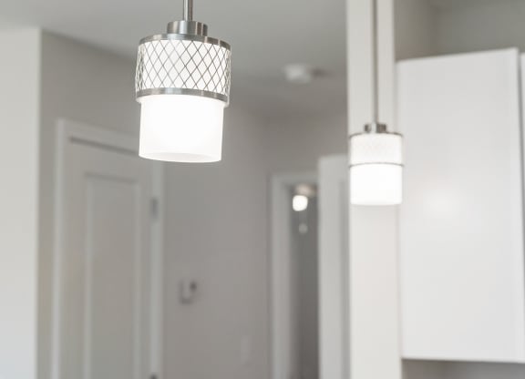 three lights hanging from a ceiling in a white kitchen