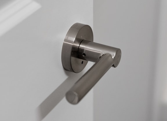a door handle in a white door with a shadow on the wall