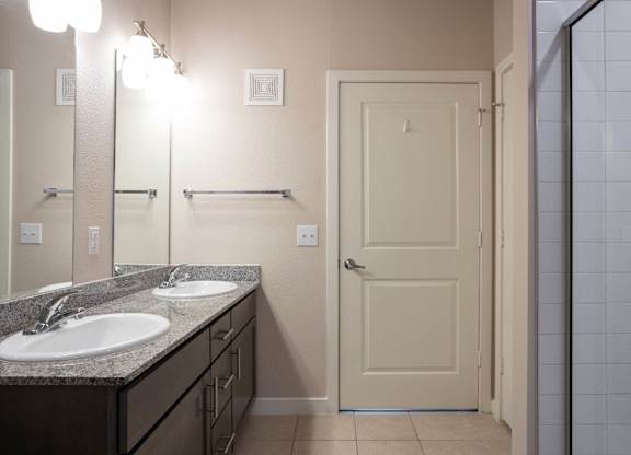 A bathroom with a sink, mirror, and door.
