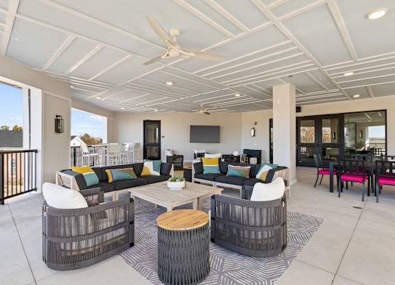 A modern outdoor living space with a white ceiling fan and a black and white striped rug.
