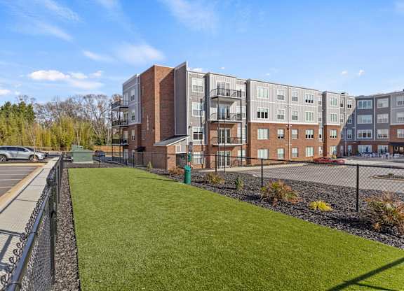 A parking lot is in front of a building with a green lawn.