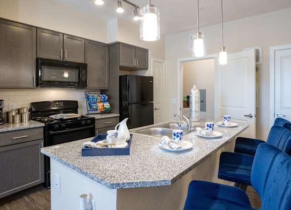 A kitchen with a granite countertop and blue chairs.