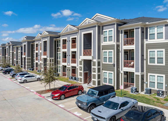 A row of townhouses with cars parked in front.