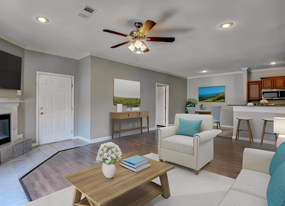 A living room with a fireplace, a couch, a coffee table, and a ceiling fan.