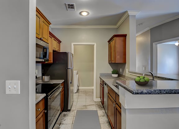 A kitchen with a black refrigerator and wooden cabinets.