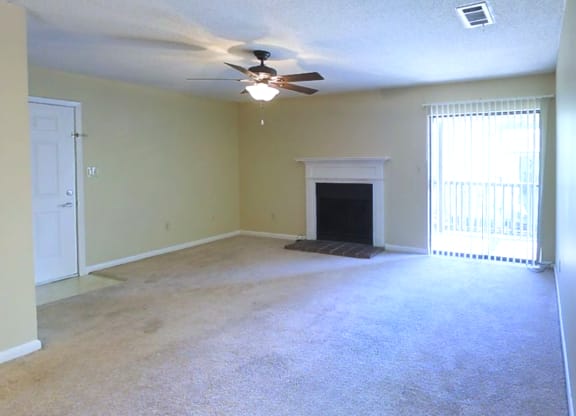an empty living room with a ceiling fan and a fireplace