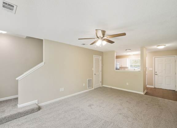 A room with a carpeted floor and a ceiling fan.