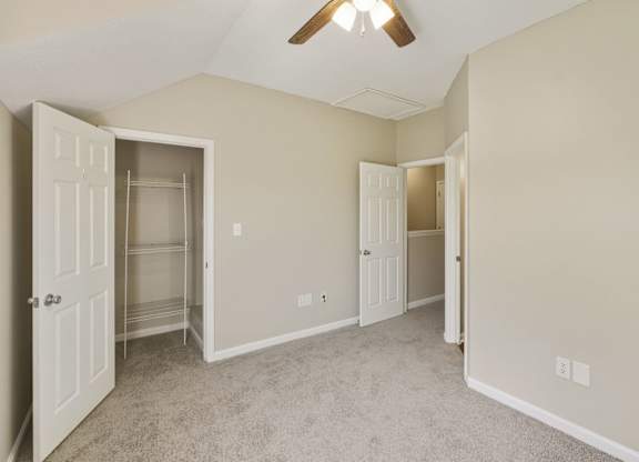 A room with a ceiling fan and two open doors.