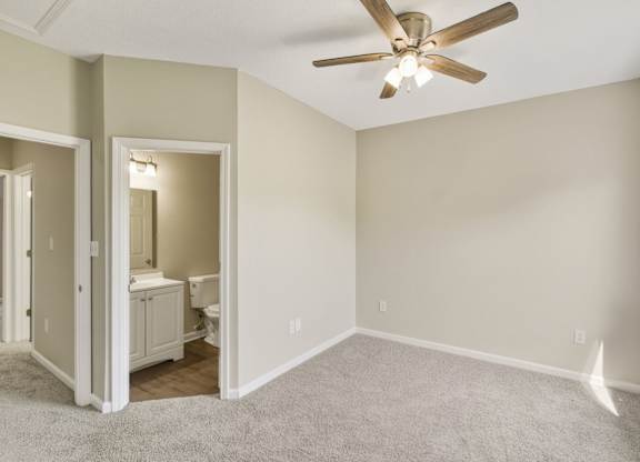 A room with a ceiling fan and a bathroom visible through a doorway.