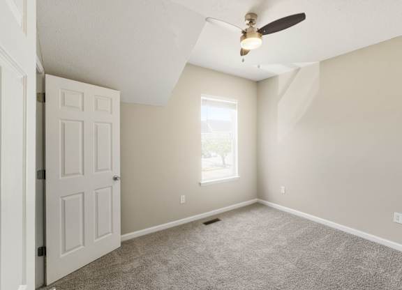 A room with a ceiling fan and a door.