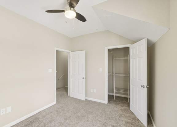 A room with a ceiling fan and two open doors.