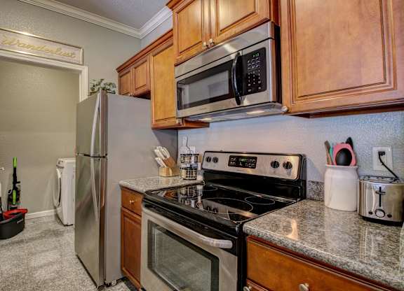 A kitchen with a stove, oven, refrigerator, and microwave.
