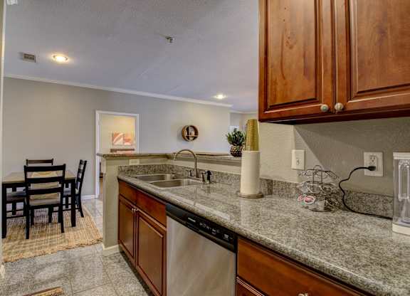 A kitchen with a sink, dishwasher, and a table with chairs.