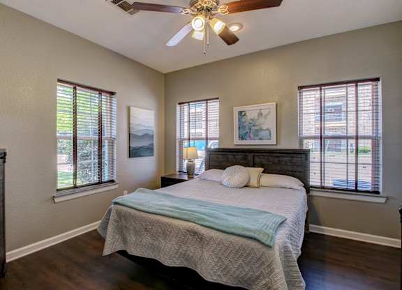 A bedroom with a bed, dresser, and a ceiling fan.