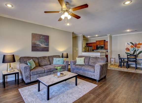 A living room with a grey couch, a coffee table, and a ceiling fan.