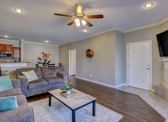 A living room with a grey couch and a ceiling fan.