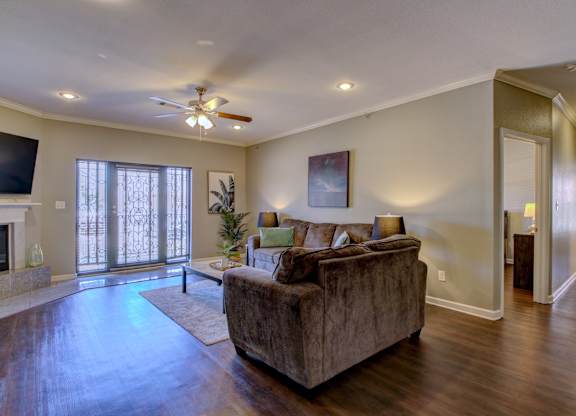 A living room with a couch, a fireplace, and a ceiling fan.