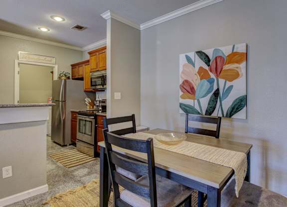 A kitchen with a table and chairs in front of a painting.