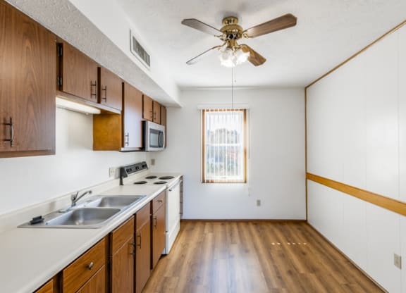 an empty kitchen with a ceiling fan and a sink