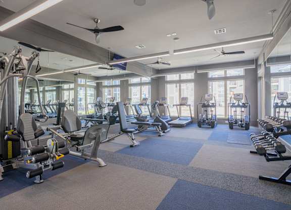 a gym with cardio equipment and windows in a building