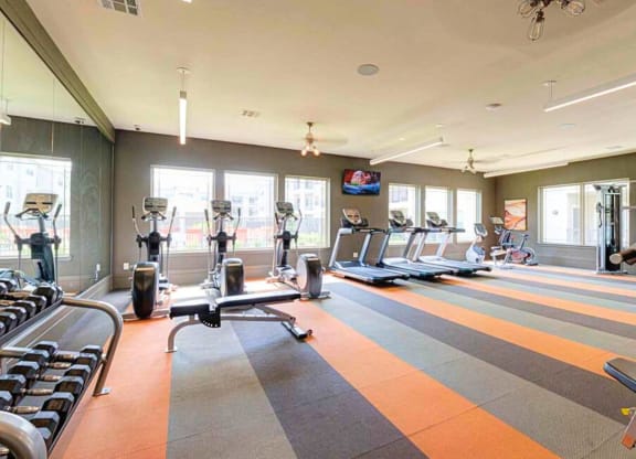 a gym with cardio equipment and windows