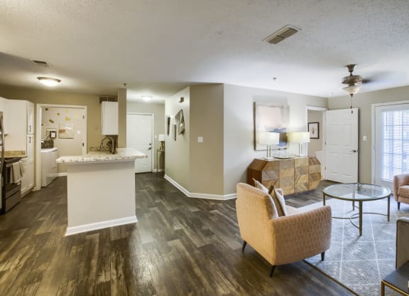a living room and kitchen area with hardwood floors and a ceiling fan