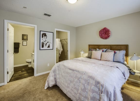 a bedroom with a large bed and a bathroom in the background