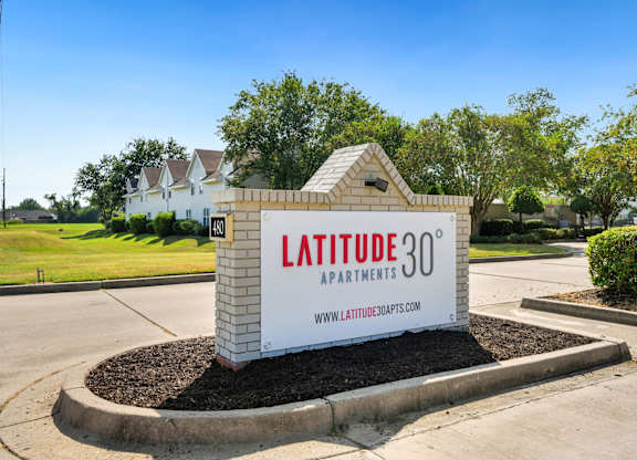 A sign for Latitude 30 Apartments is displayed in front of a building.
