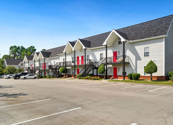A parking lot in front of a building with red doors.