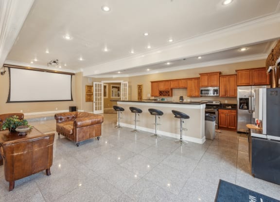 a large kitchen and living room with a bar and a projector screen