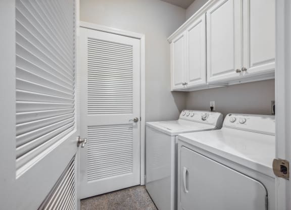 a laundry room with a washer and dryer and white cabinets