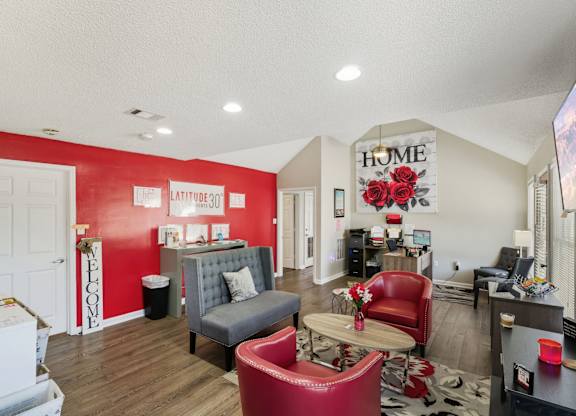 A living room with a red couch and a grey armchair.