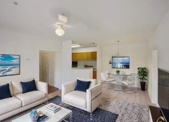 A living room with a white couch and a blue vase on the coffee table.