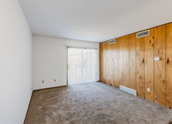 an empty living room with a wooden wall and a sliding glass door