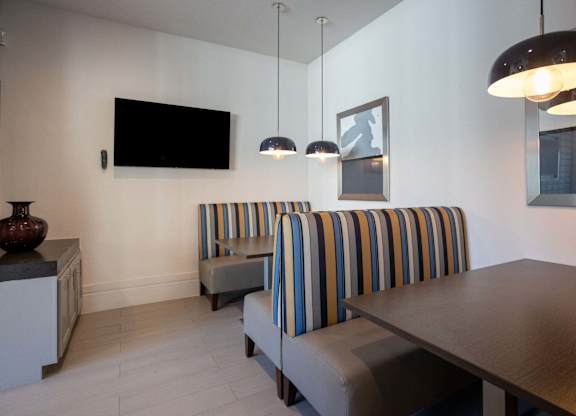 A living room with a striped couch and a television mounted on the wall.