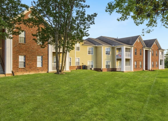 a grassy area with trees in front of a brick building