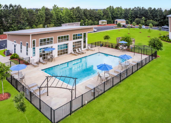 an aerial view of a resort style pool with lounge chairs and umbrellas
