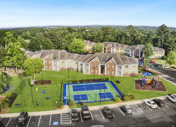 an aerial view of a tennis court and parking lot in front of a row of houses