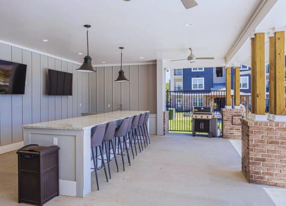 a long bar with chairs in a room with a grill