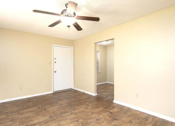 an empty living room with a ceiling fan