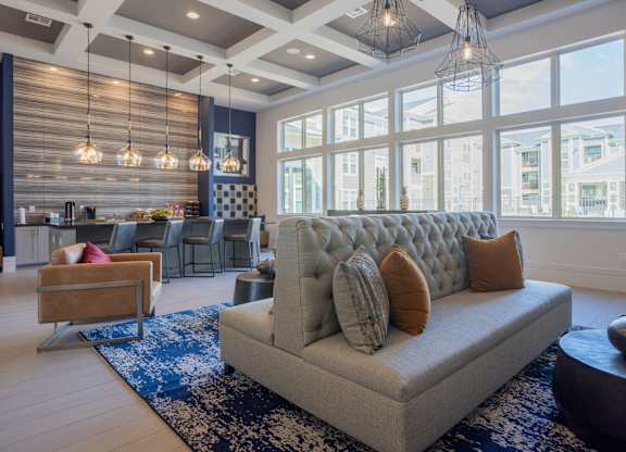 a living room with a couch and chairs in front of large windows