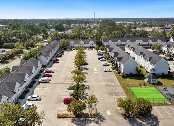 A parking lot in front of a residential area with cars parked.