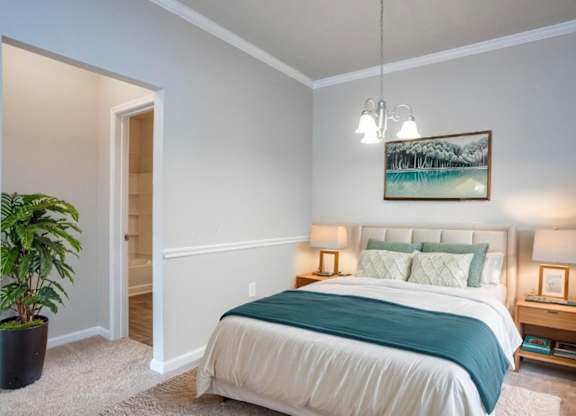 A bedroom with a bed, nightstand, and a painting on the wall.