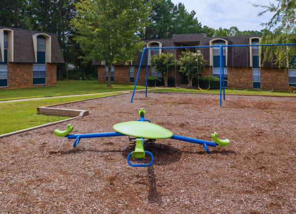 a playground with a swing set in front of a building
