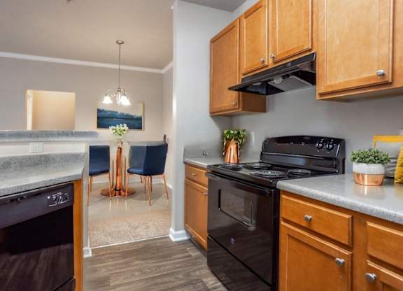 A kitchen with a black stove top oven and wooden cabinets.