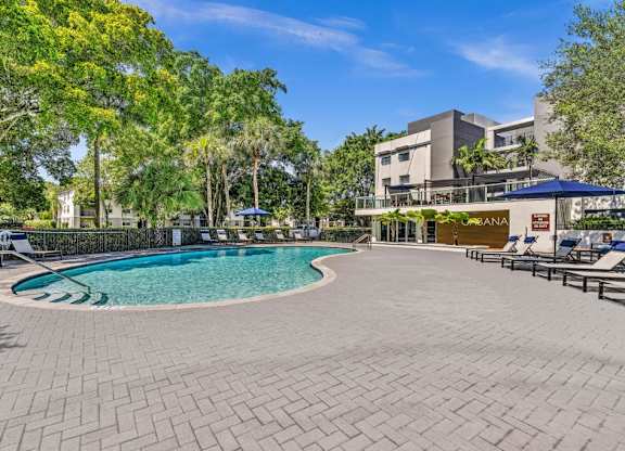 A pool surrounded by a brick patio and trees.