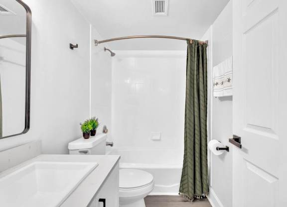 A white bathroom with a green curtain.