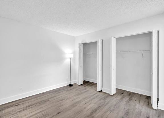 A room with a floor lamp and three open doors.